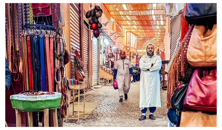 Callejón del zoco de Marrakech con bolsos de cuero y hombres con chilaba