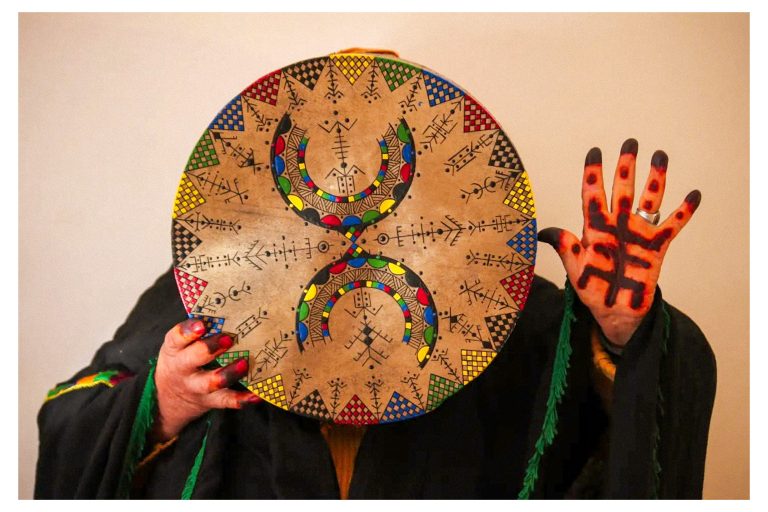 Manos pintadas con símbolos amazigh sujetando un pandero decorado en Afus Art, Tinghir