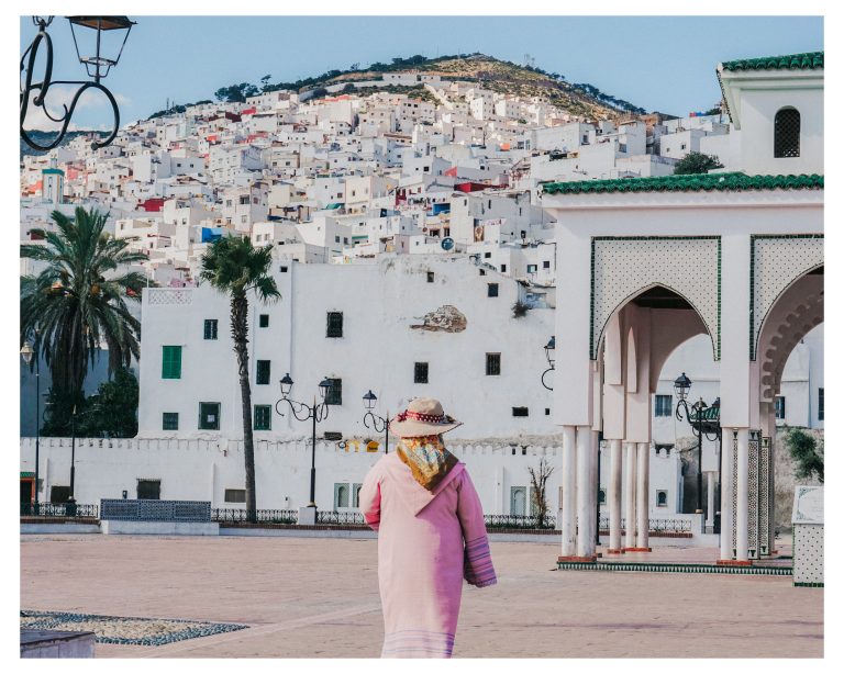 Mujer con chilaba rosa frente a la medina blanca de Tetuán